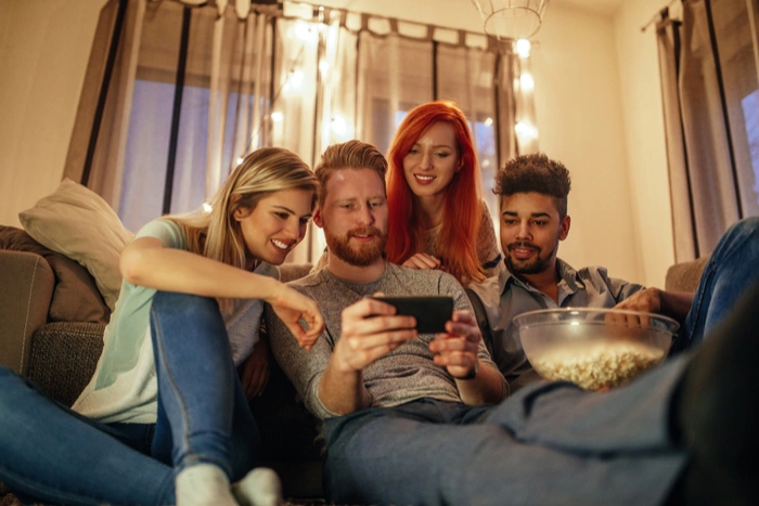 Friends watching a streamed movie together in a living room at night
